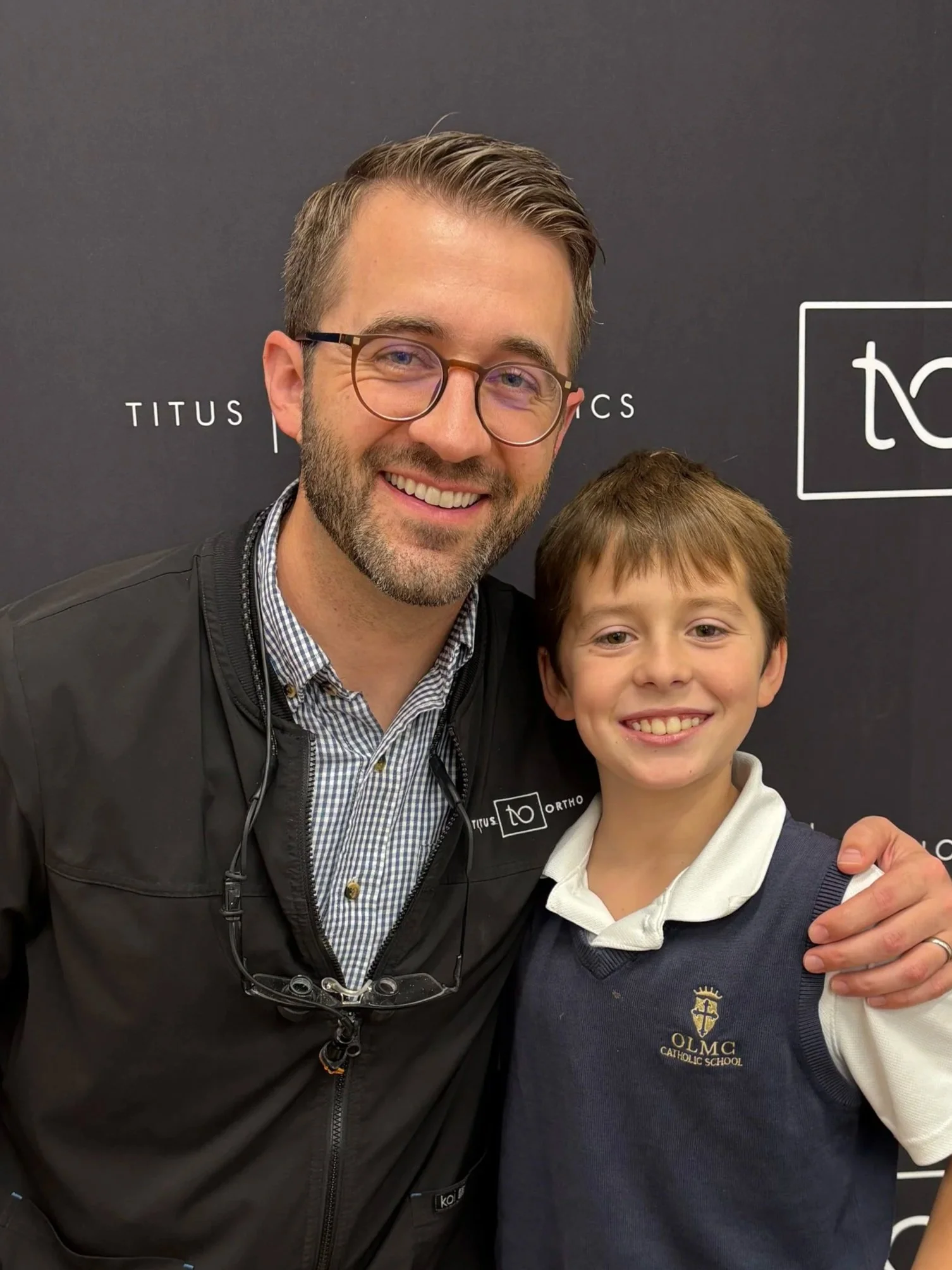 two people standing side by side smiling in front of a backdrop - How to Get Braces Glue Off Teeth in Westfield, IN