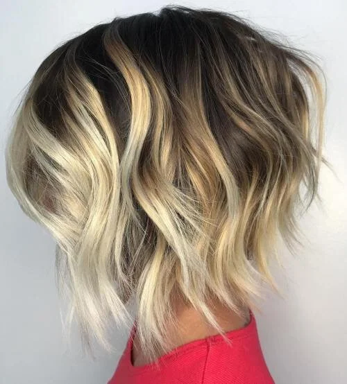 Coiffure blonde mi-longue avec des vagues souples.