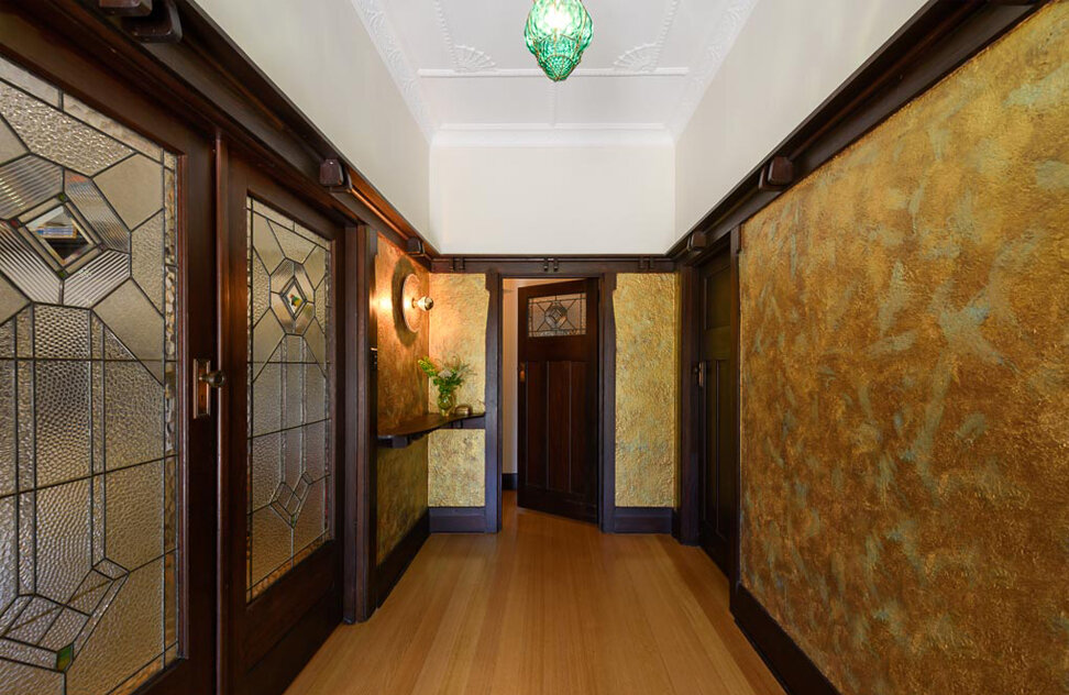 The dazzling entry features a recreated "tiffoney" finish to the walls, the original emerald glass light fitting, plastered ceilings and detailed timber trim. Image: VSTYLE
