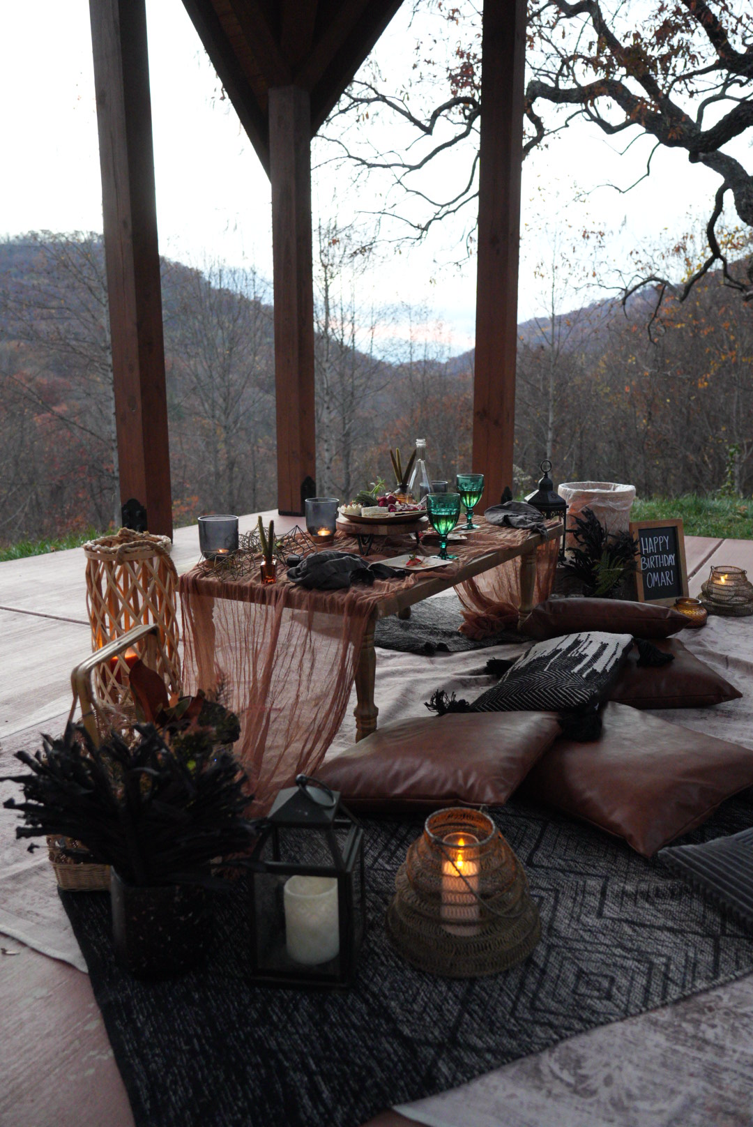 Intimate mountain view picnic setup with candles and birthday decor under a wooden pavilion in Asheville