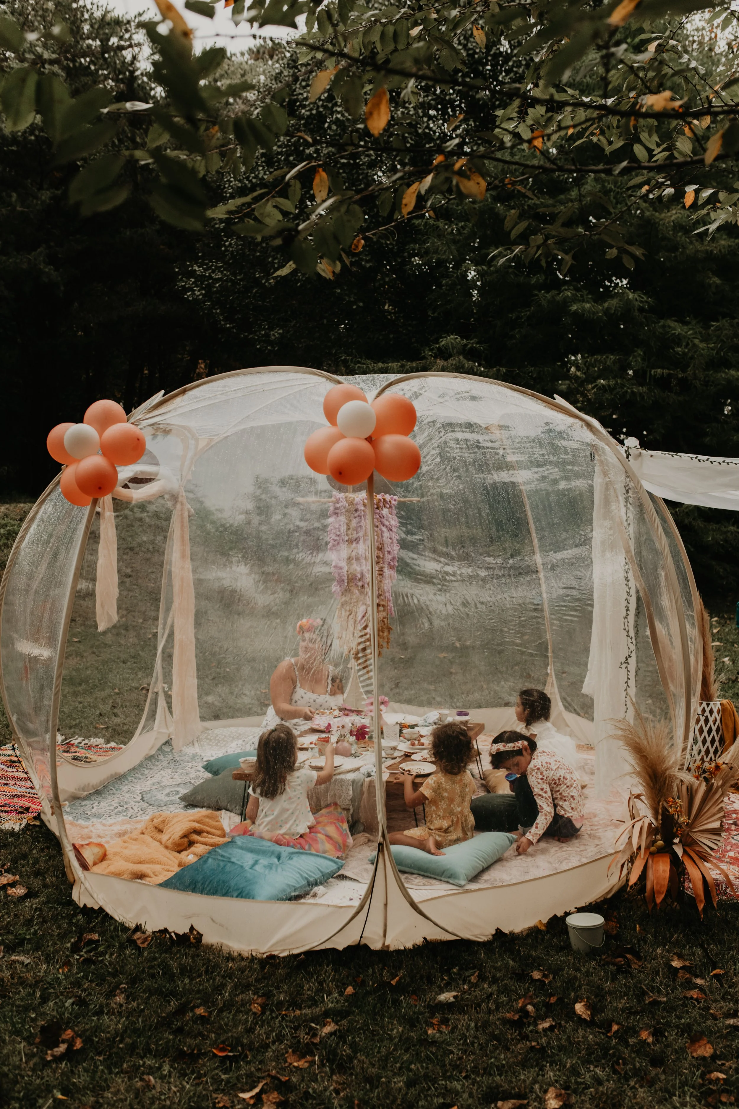 Children enjoying a styled tea party picnic in Asheville with low table seating, decorative florals, and whimsical birthday decor.
