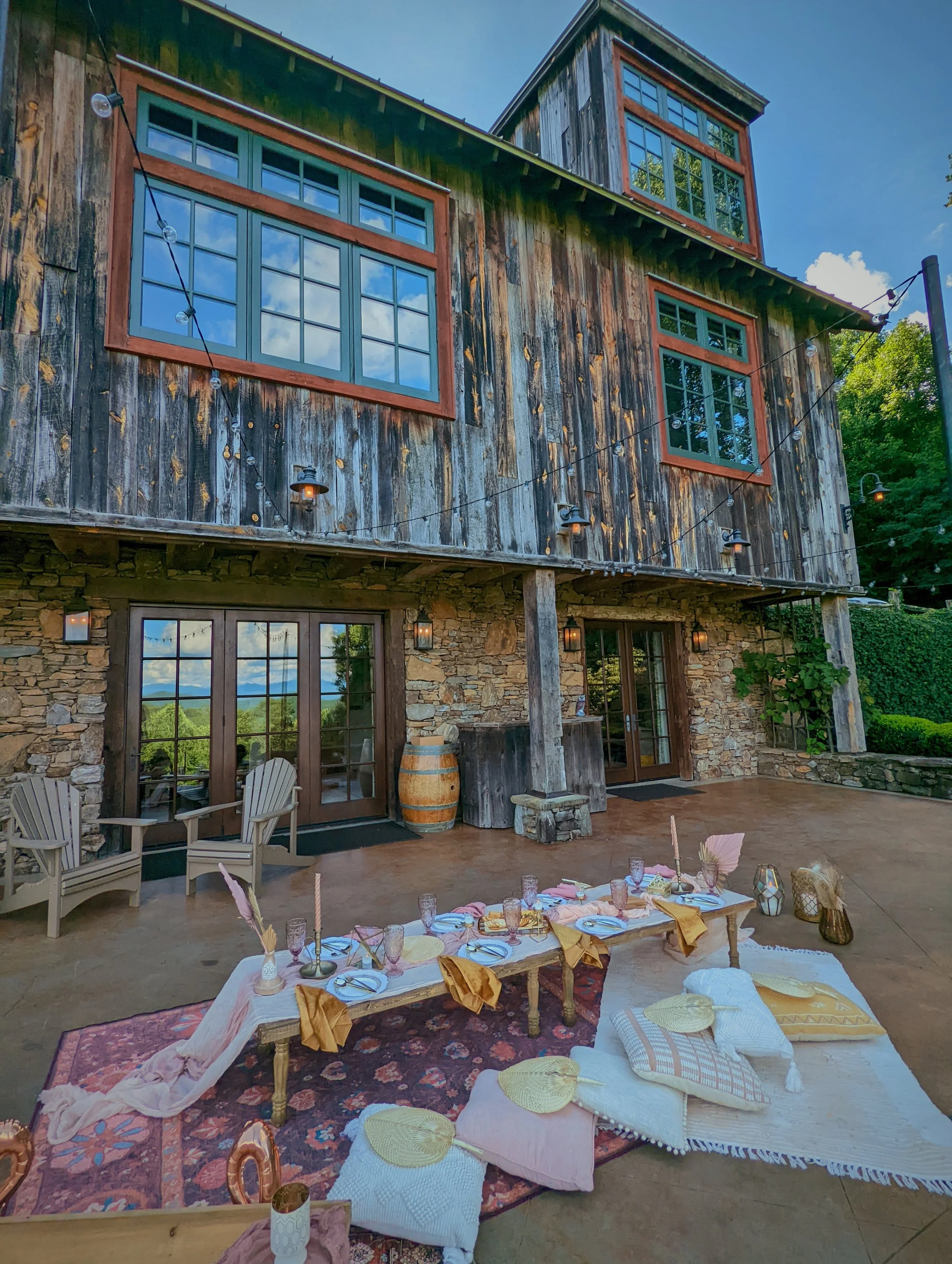 Luxury proposal picnic setup under a timber pavilion with mountain views in Asheville, featuring layered rugs, candles, pampas grass, and curated decor.