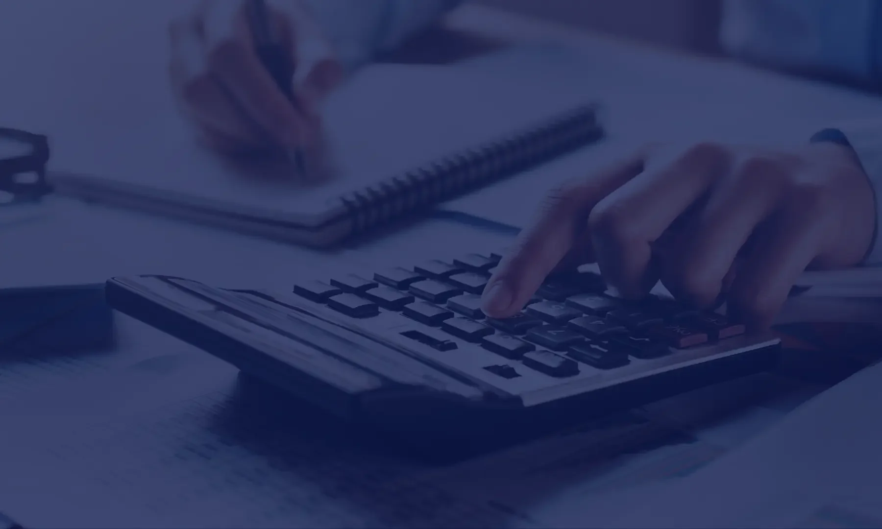 Closeup of a person working on a quote request using a calculator, notepad, and pen.
