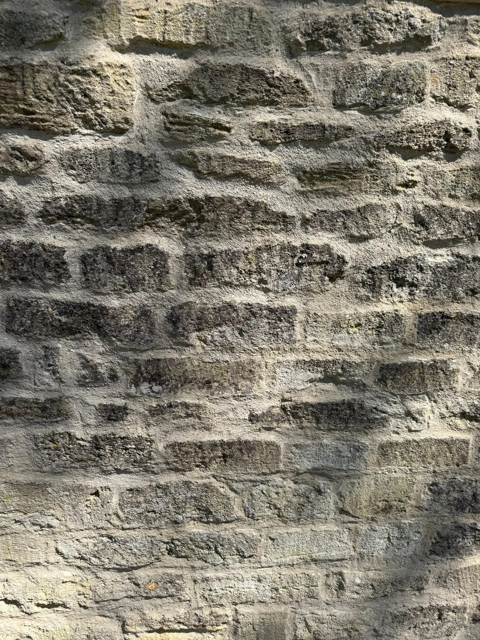 Close-up of a textured stone wall with alternating layers of light and dark stones.
