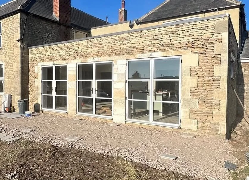 Brick house with three large glass sliding doors and a gravel yard.