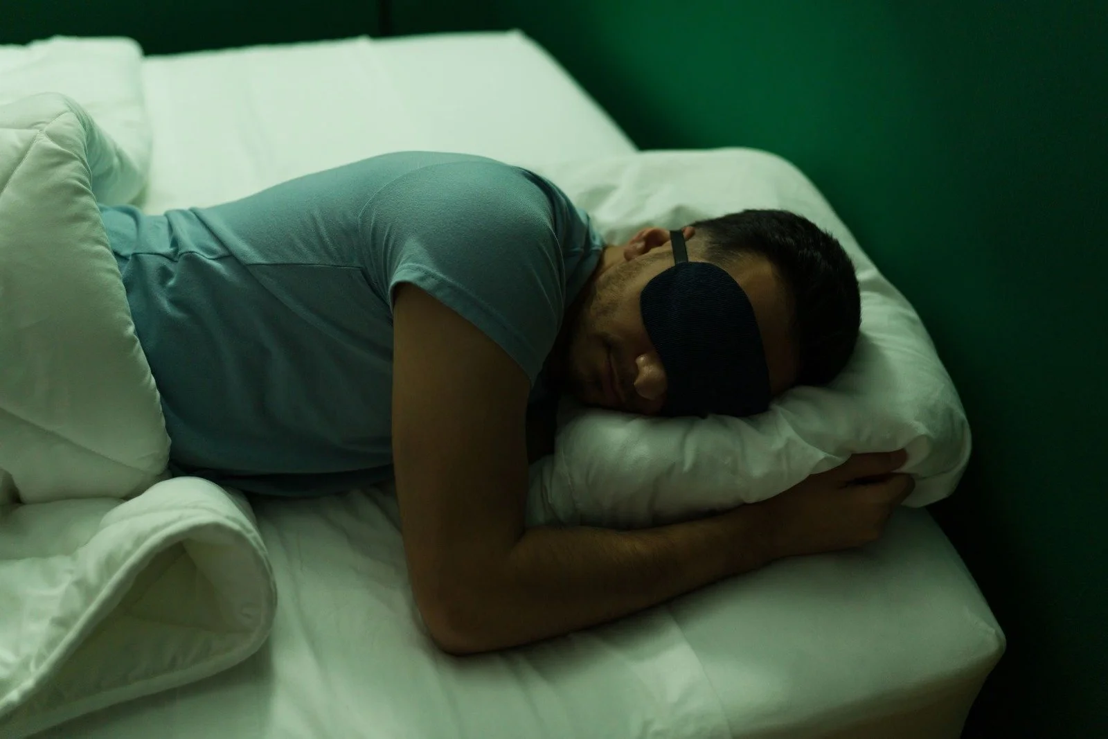 a man sleeping with an eye mask on as darkness is important for quality sleep
