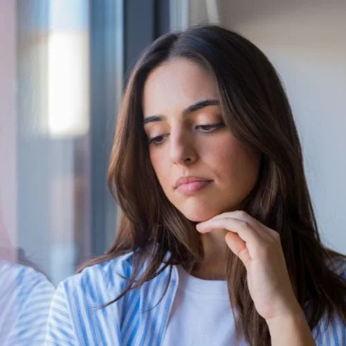 Thoughtful woman by a window on the anxiety therapy page