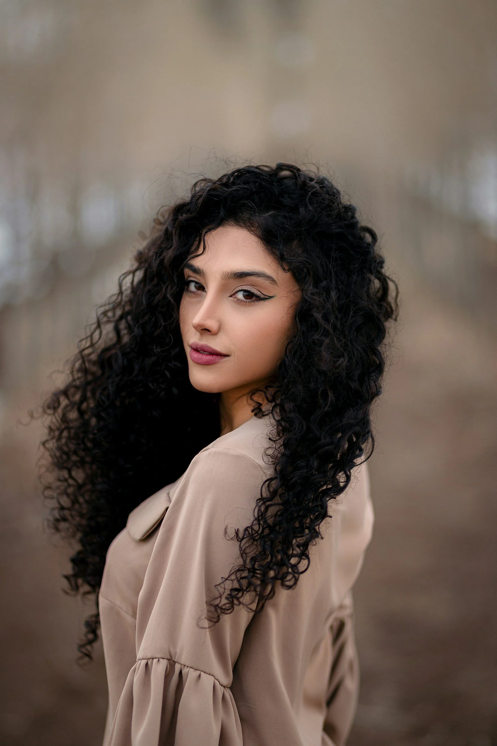 Mulher com cabelo longo e preto segurando um bebê sorridente e brincalhão, ambos em preto e branco, contra um fundo simples.