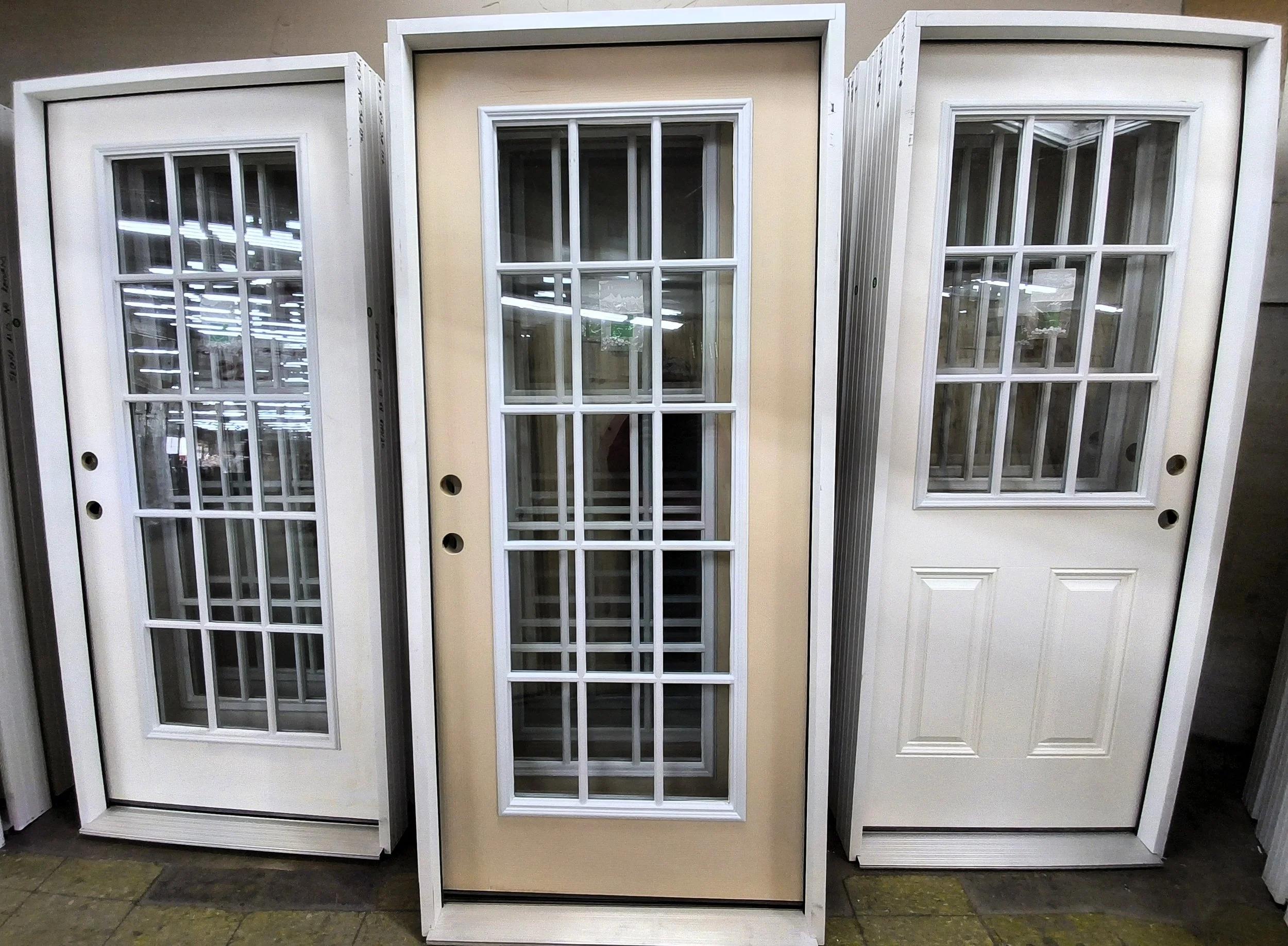 Various wooden doors in a hardware store, including a red barn door, natural wood, and dark stained options, mounted on display rails.