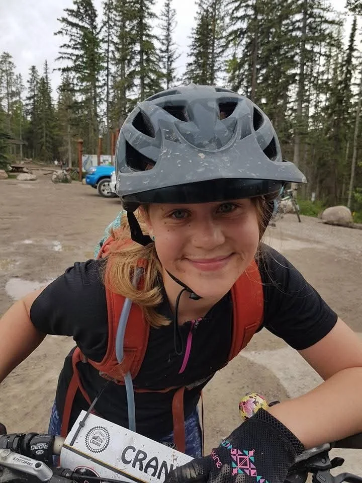 Mud speckled face of young female mountain bike rider