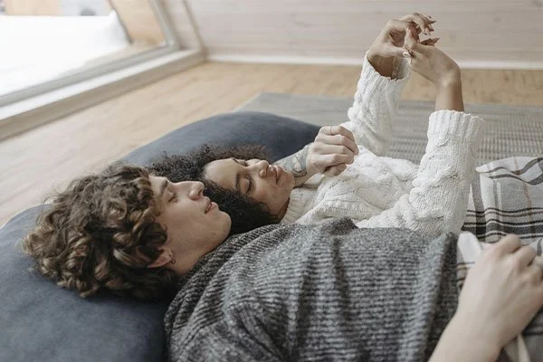 Couple lying down admiring the ring on the woman's finger represents how a couples therapist in LA can help in your strengthen your marriage.