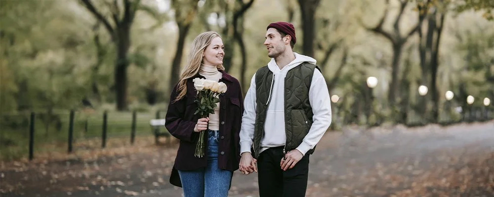 Couple on a date, walking while holding hands in the park, represents how you can find support for your love life through dating coaching in LA.