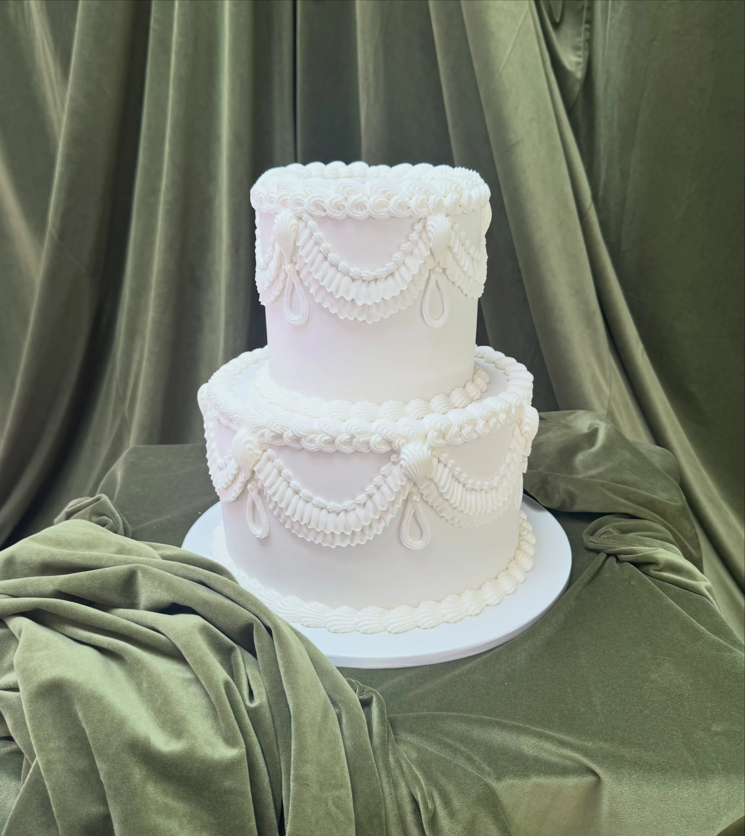 WHITE!
A new favourite it vintage piping 
For a true white I use royal icing which is a meringue of egg white and sugar
cute edible print on top and love the green drape, perfect cake table styling
