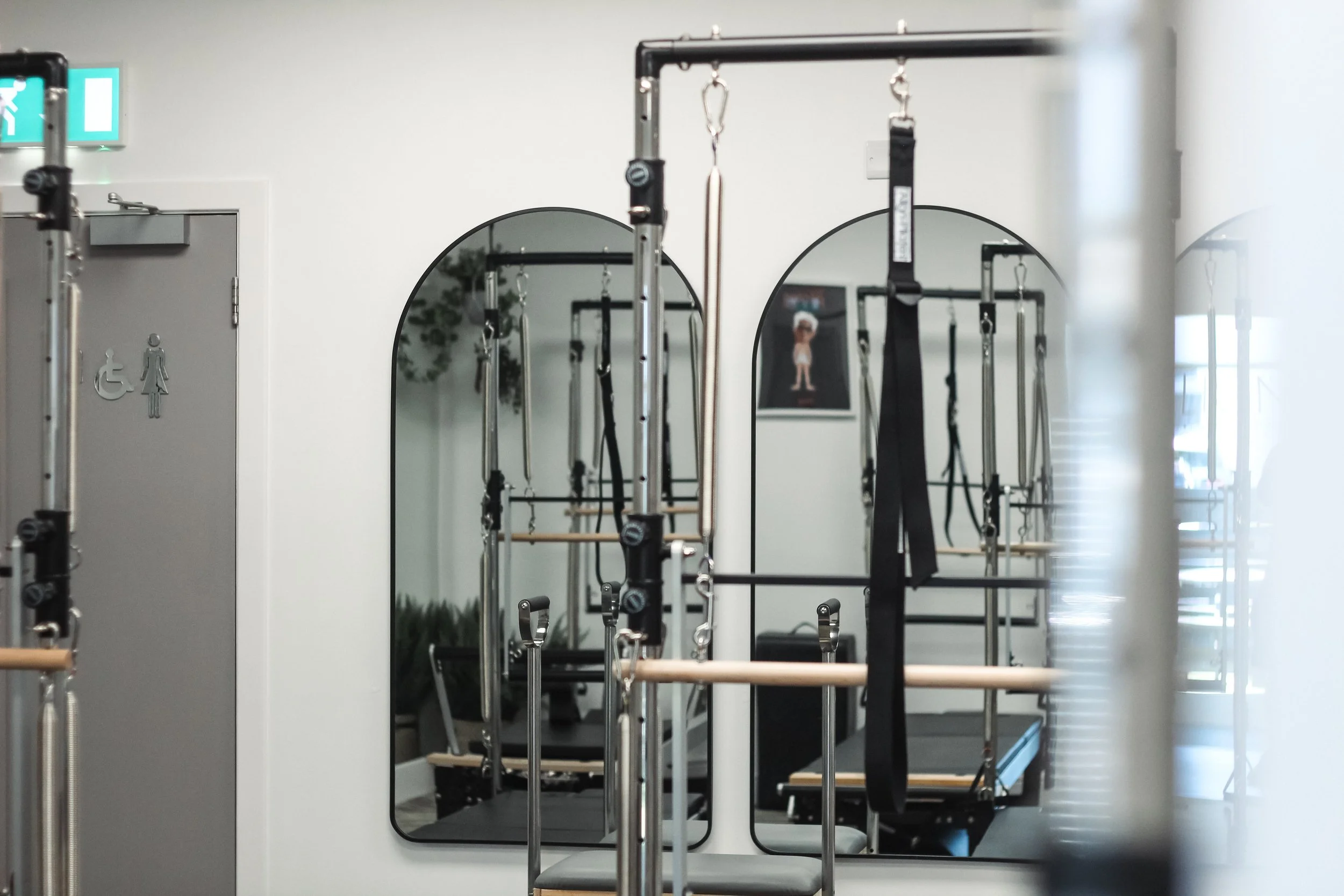 Pilates reformer machines in a fitness studio, reflected in a mirror.