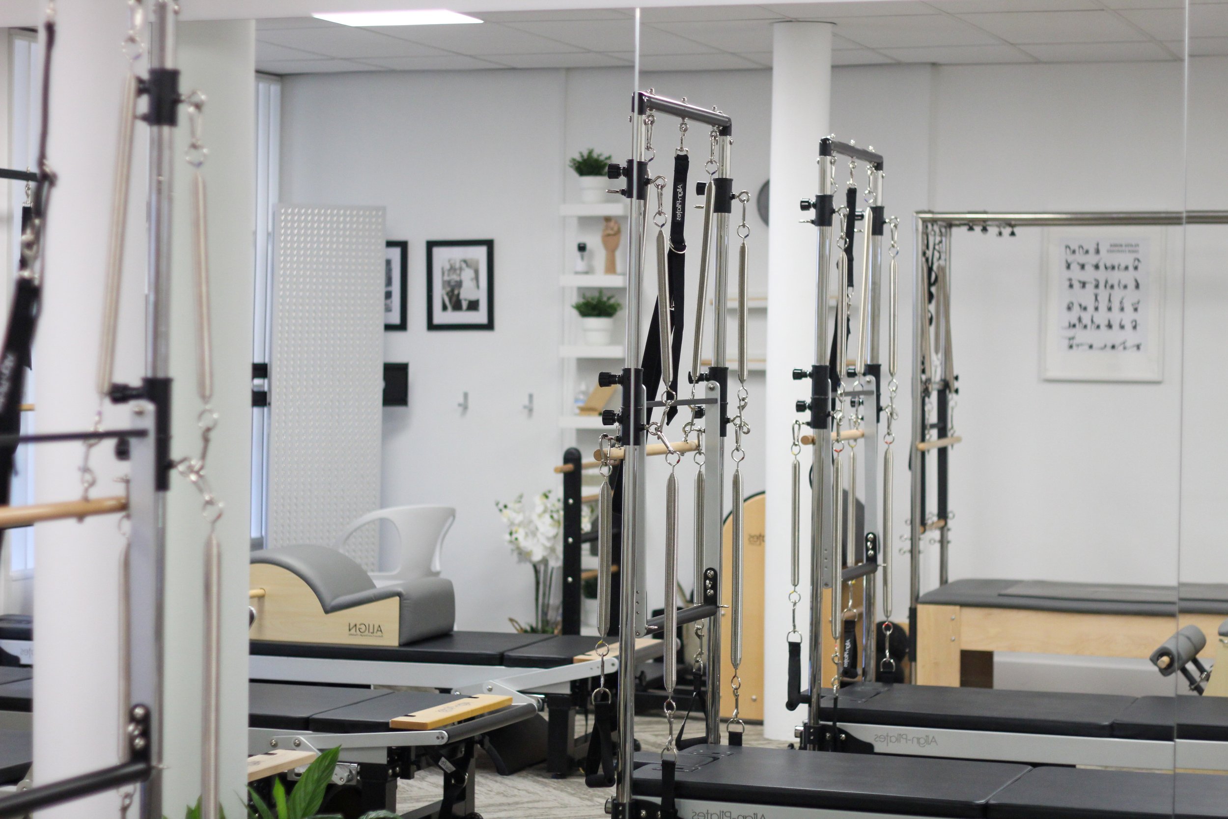 A physical therapy or rehabilitation clinic with various equipment including metal bars and chains for exercise and therapy sessions, a chair, and framed pictures on the wall.