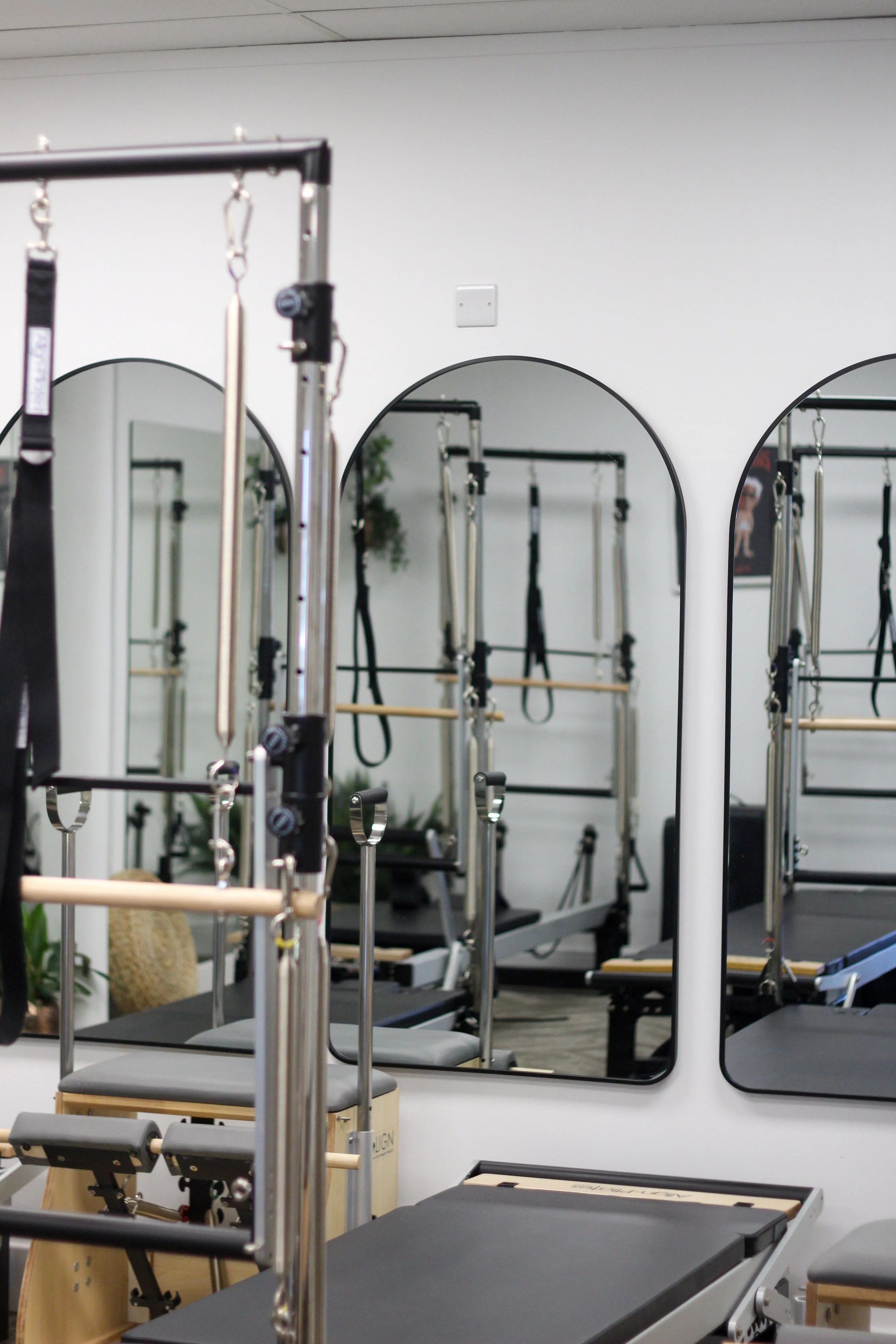 Pilates studio with mirrors, reformer machines, and fitness equipment.