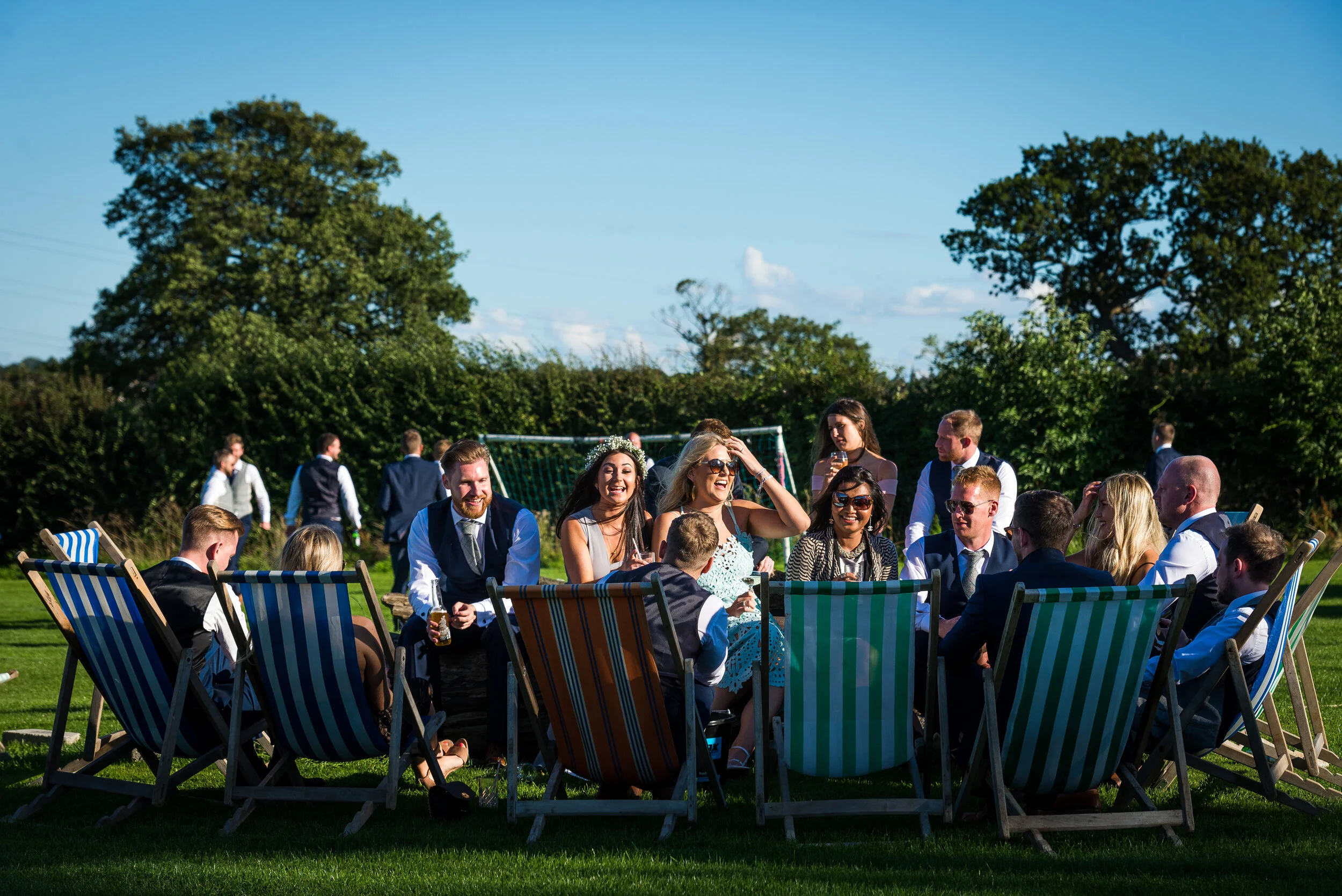 sunny wedding in Harrogate, North Yorkshire, bride and groom in deckchairs with wedding guests