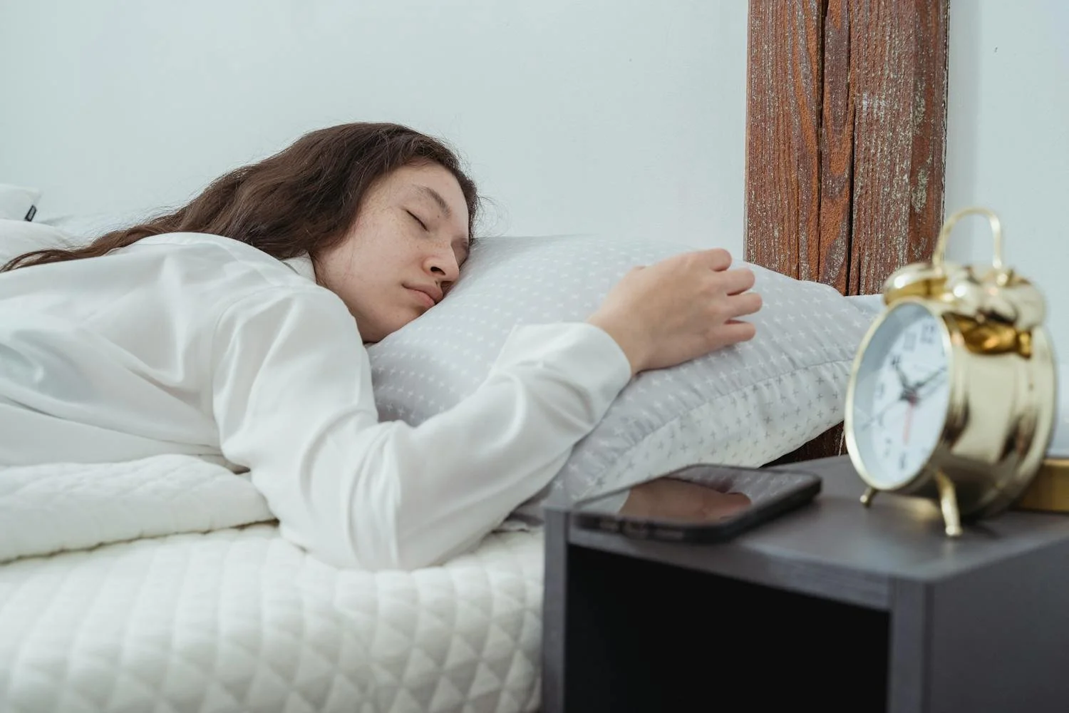 Student sleeping early with alarm clock beside bed