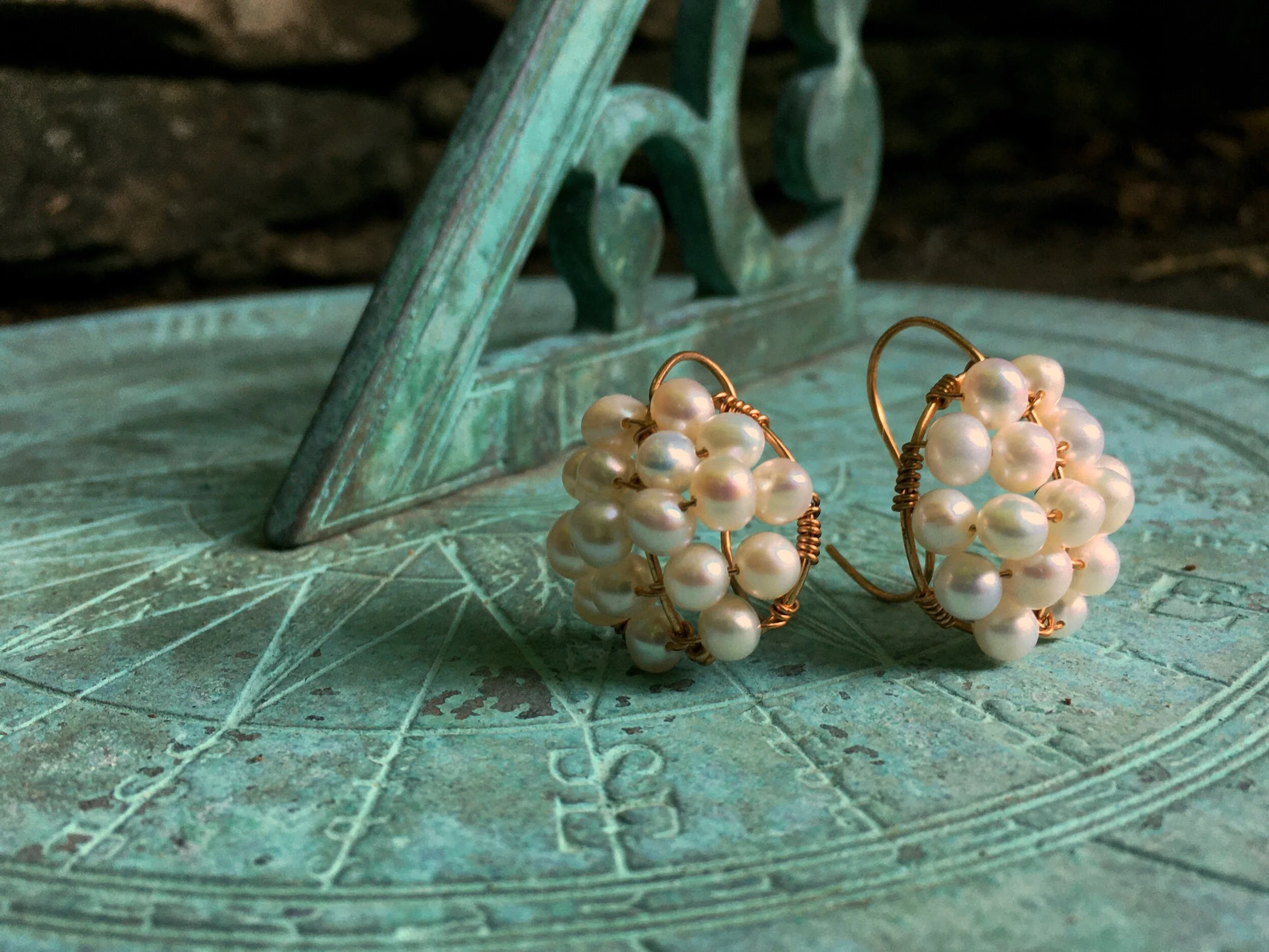 Ancient style pearl cluster earrings sitting on a sundial