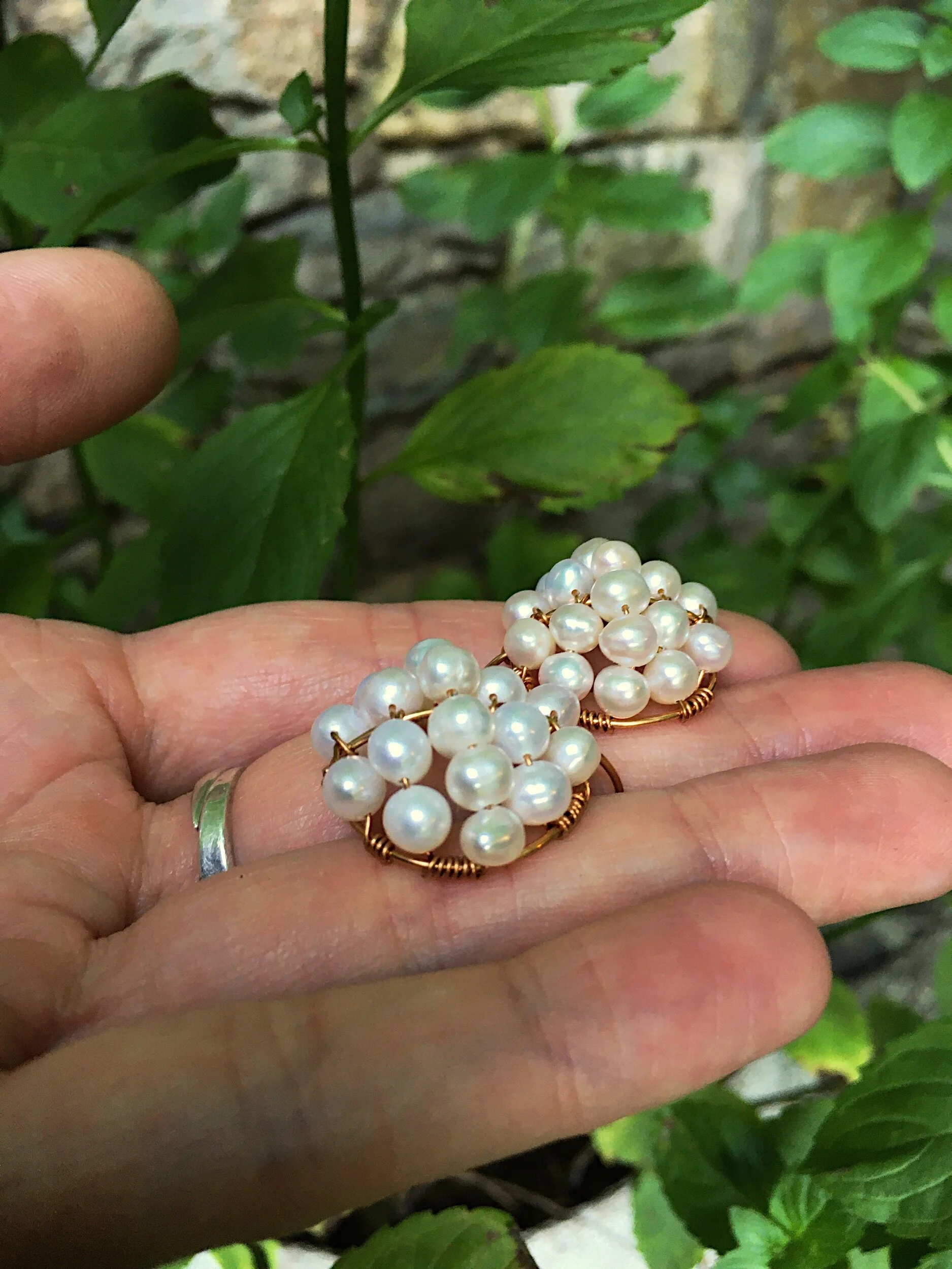 pearl cluster earrings sitting on a hand for scale. The earrings are about one inch long.