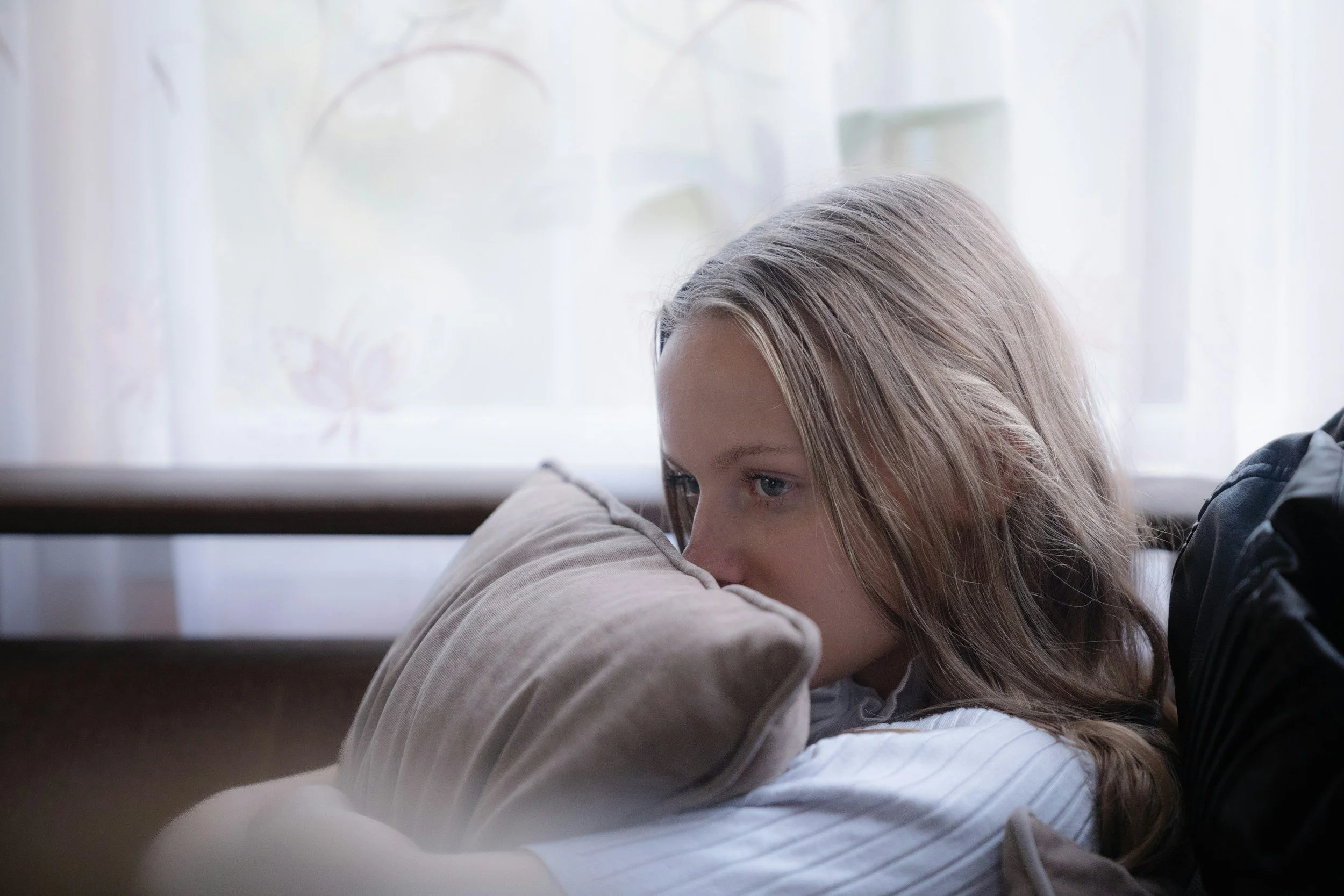 Sad woman sitting in a chair holding a pillow to her face. Learn how couples therapy in Sugar Land, TX can help you learn why you and your partner keep having the same argument and reconnect.