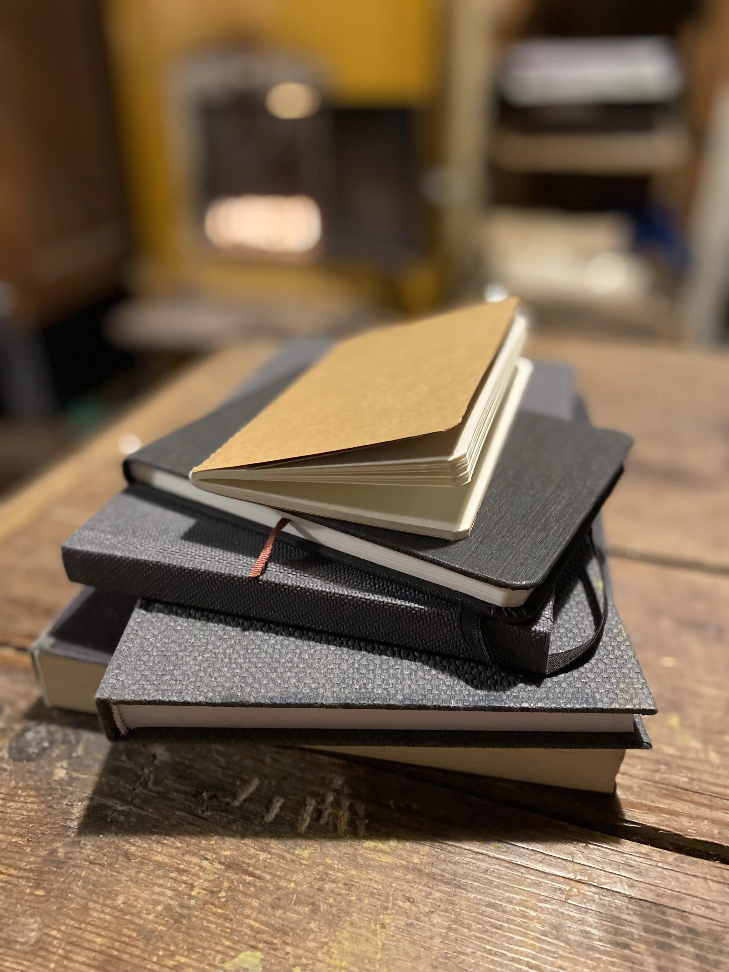 Pino muistikirjoja puisella pöydällä.