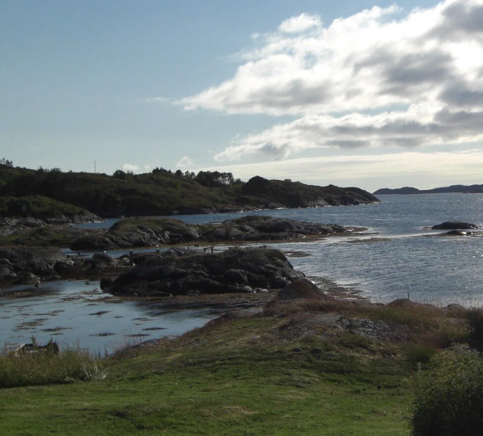 Sørlig kystlandskap med steiner, vann og skyer