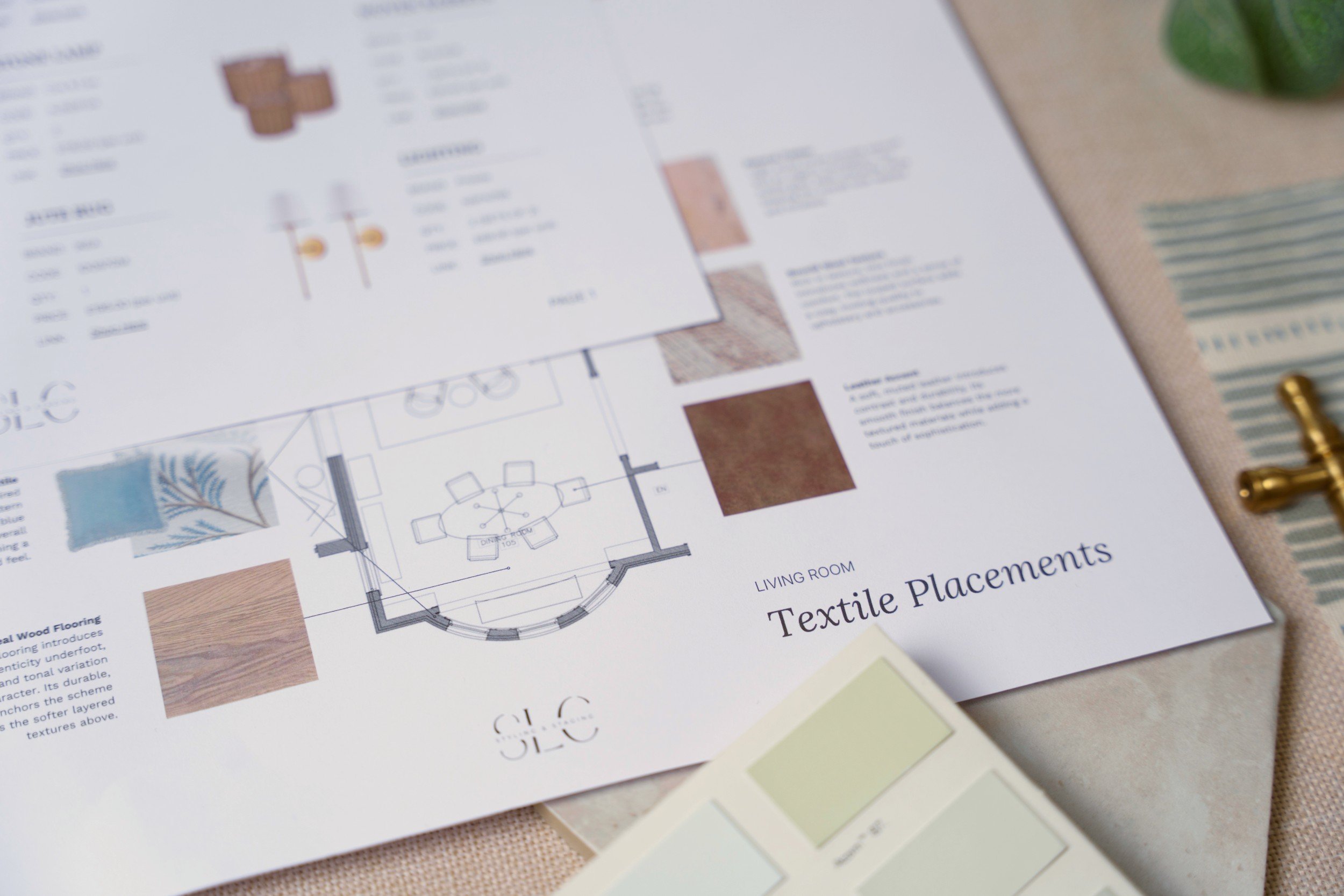 A printed interior design floor plan with fabric and color samples nearby.