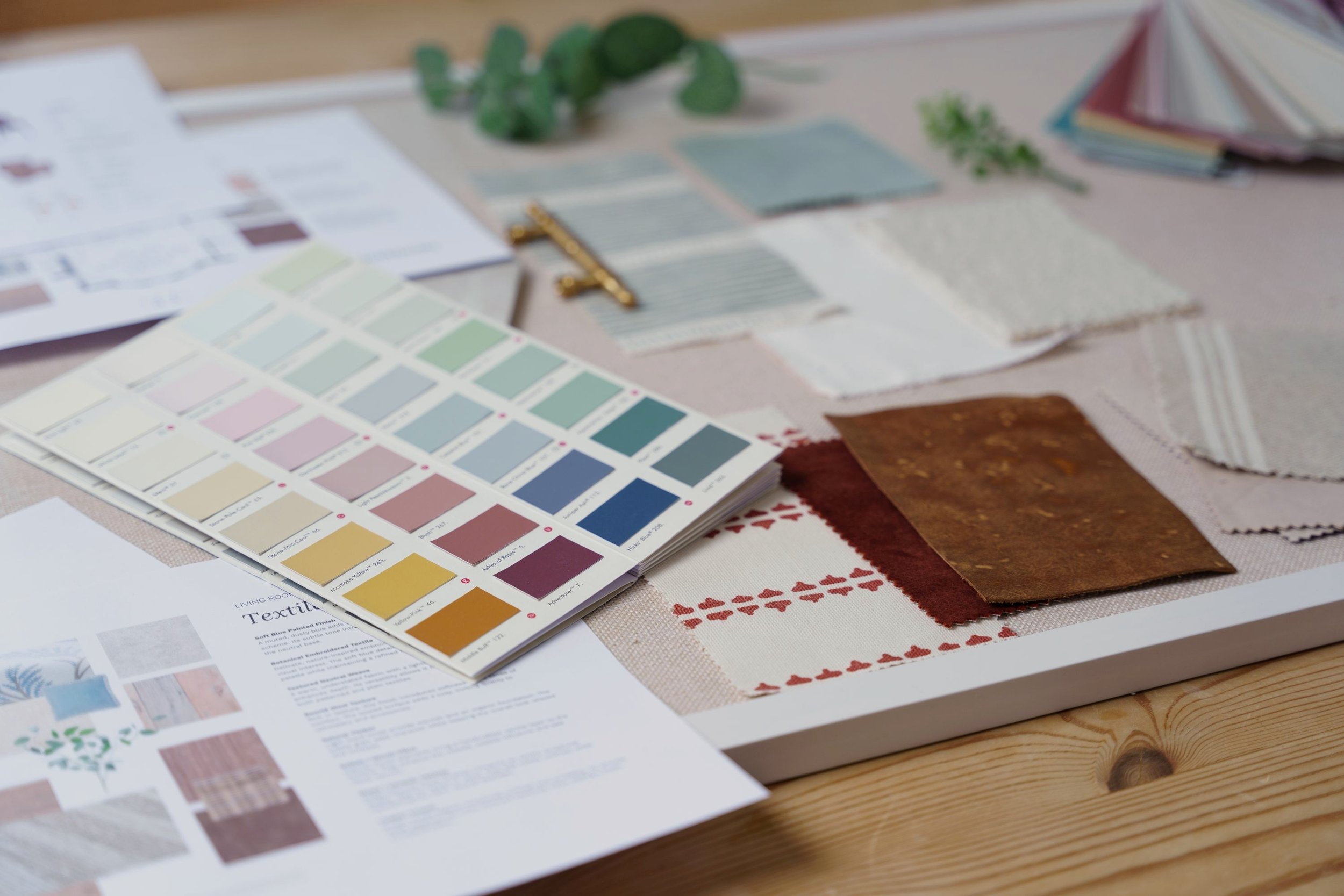 Color swatches, fabric samples, and color palette guide spread out on a table for interior design or decorating project.