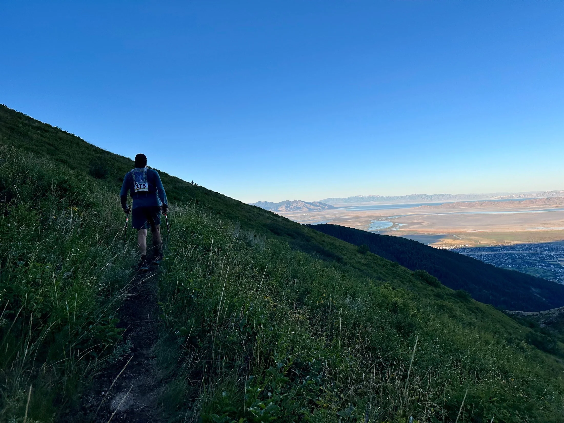 Ultrarunner John Mathis cresting the first climb toward Bair Canyon at sunrise during the Wasatch Front 100 in Utah, valley below.