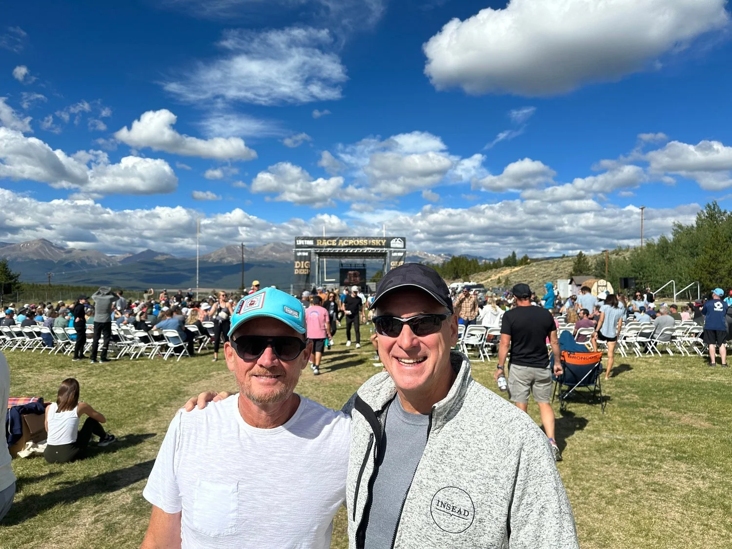 John Mathis and David Green at Leadville 100 race check in, Colorado mountains and the Race Across the Sky banner behind them.