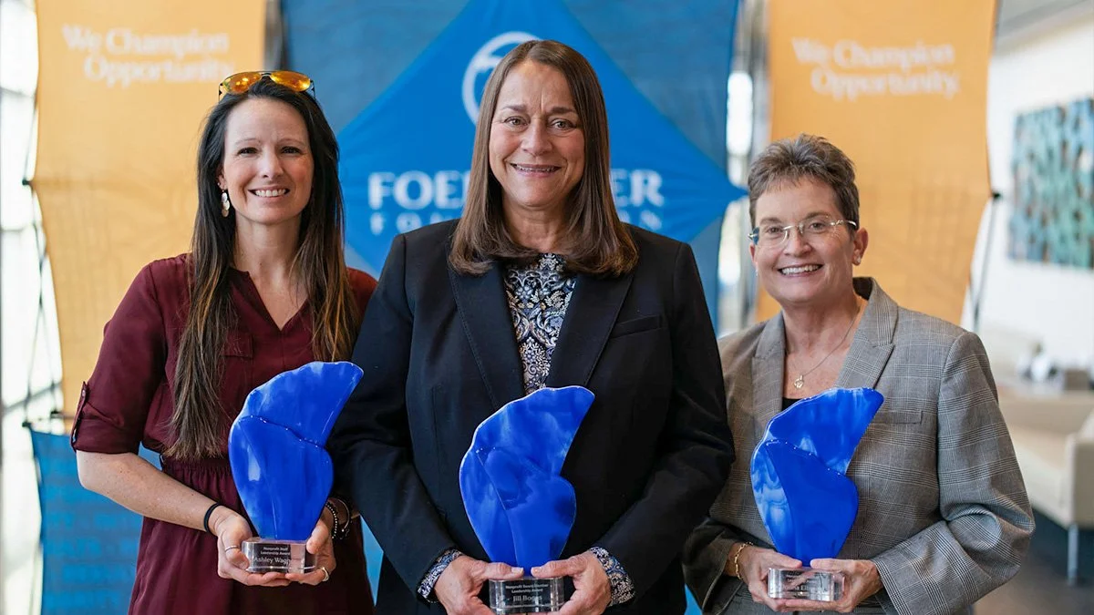 Group photo of the three leadership award recipients posing each holding their blue, abstract award