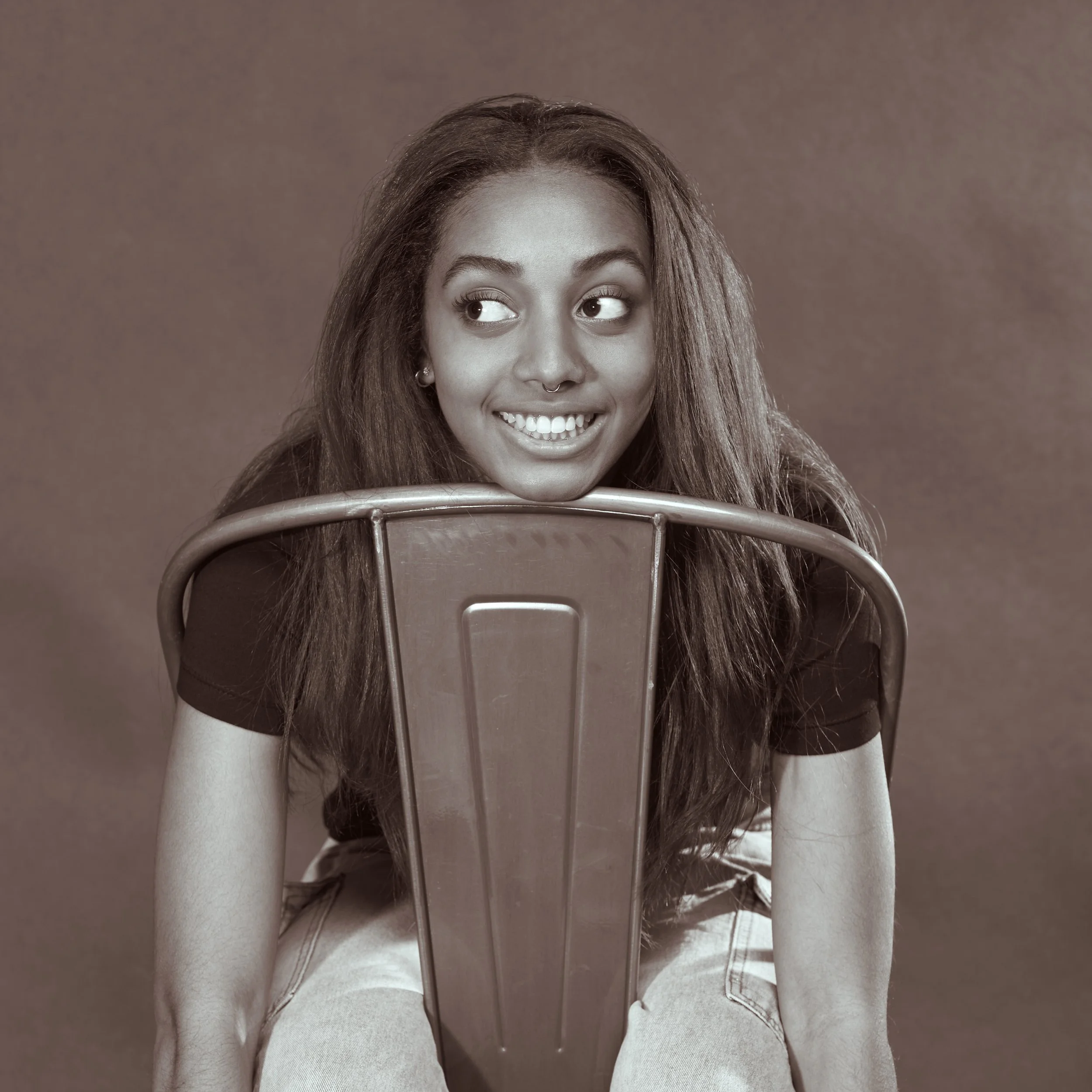 A black and white photo of me sitting backwards on a chair, resting my head on it.