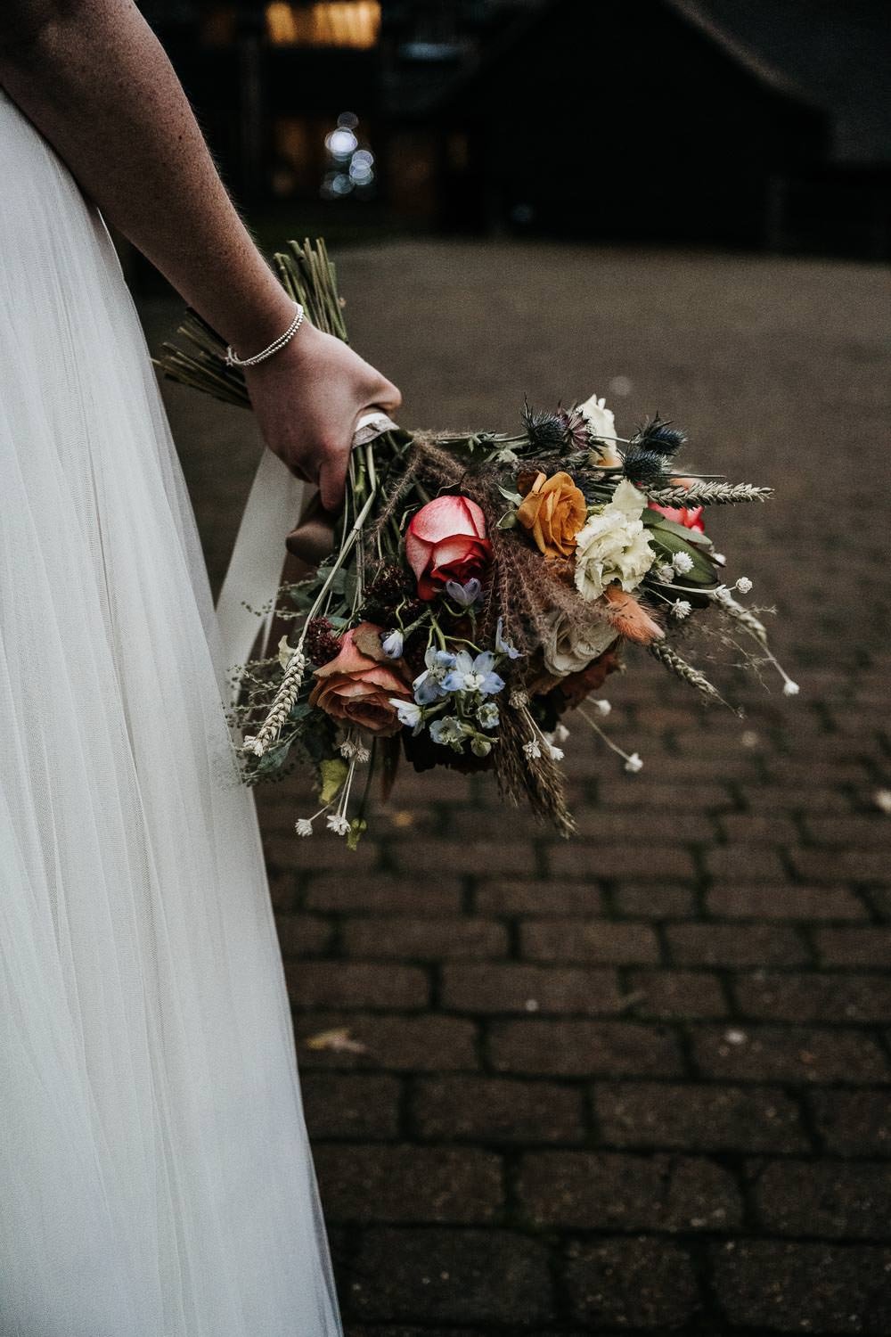 Bouquet of flowers held beside wedding dress
