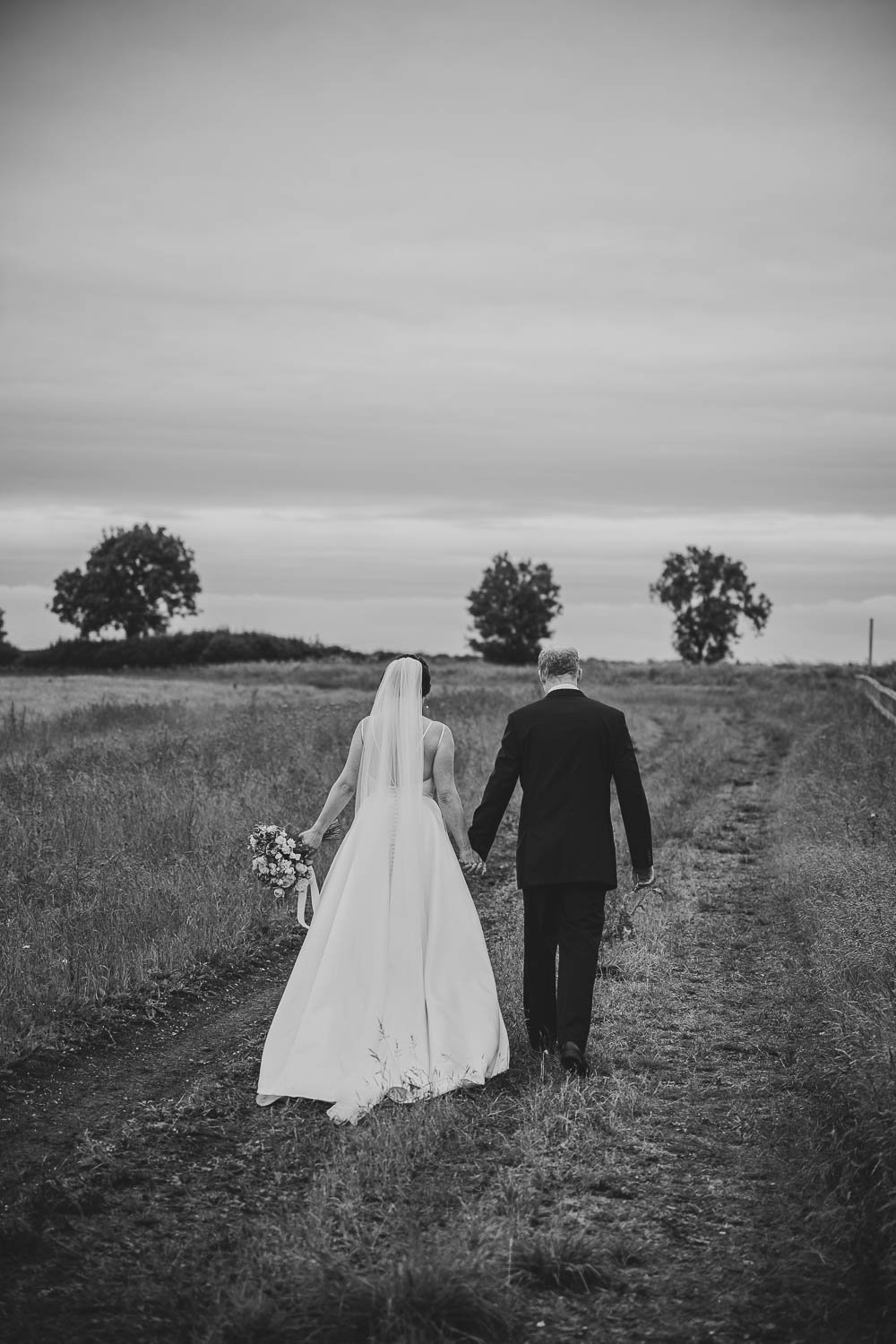 newlywed couple walking in the Cambridgeshire fields at Hardwick Moat