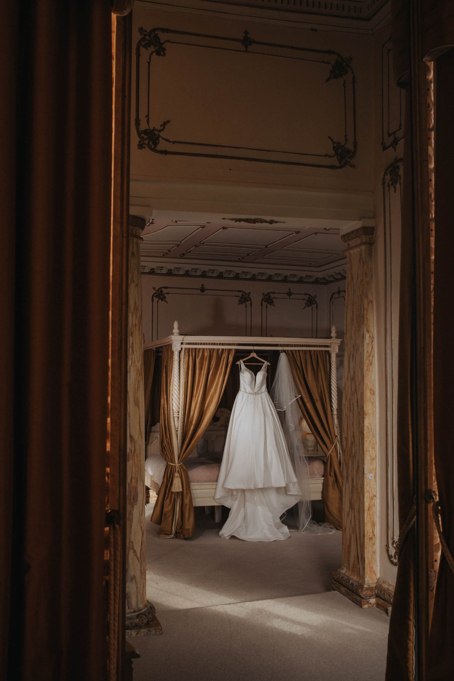 Stella York wedding dress hanging on four poster bed at Gosfield Hall Essex