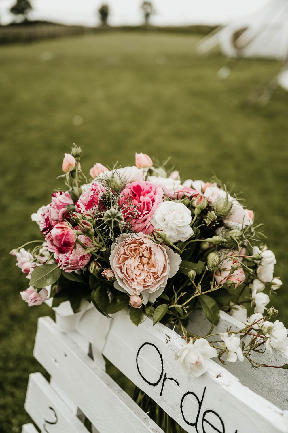Bouquet of wedding flowers placed on a white rustic wooden pallet decor.