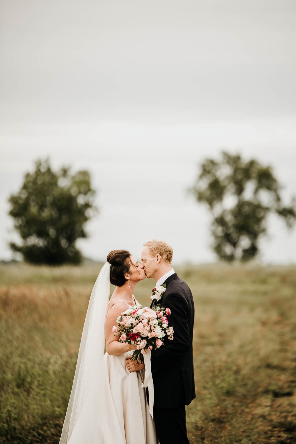 Groom kissing bride in country field