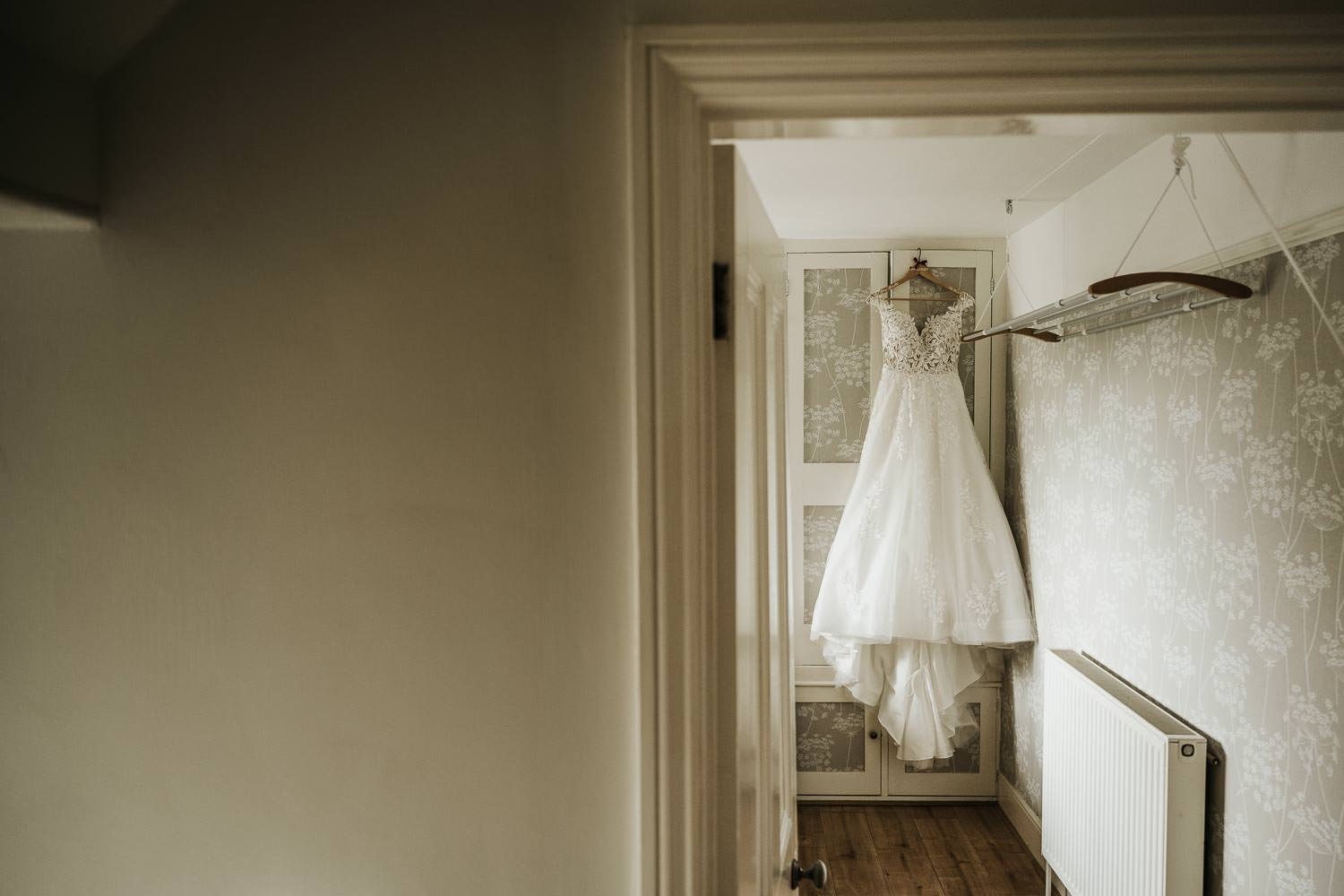 Wedding gown seen hanging through doorframe of bedroom