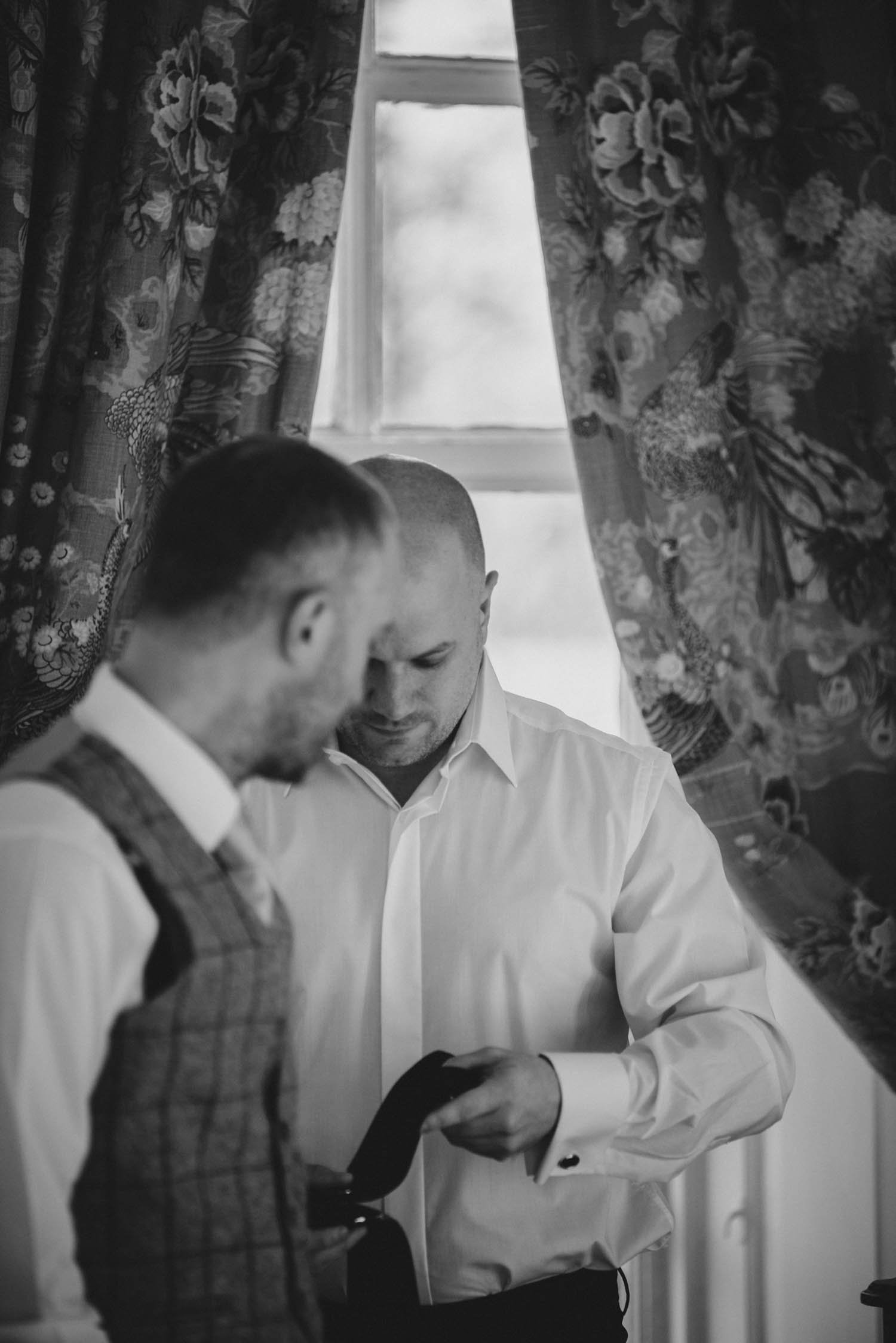 Groom getting tie ready with best man at Gosfield Hall