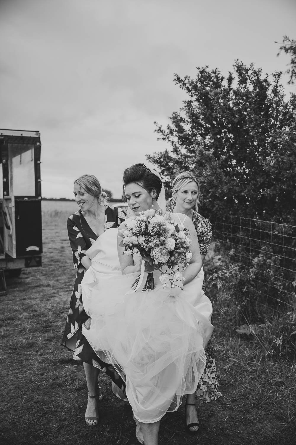 Bride holding wedding dress up from the mud at Hardwick Moat Cambridgeshire