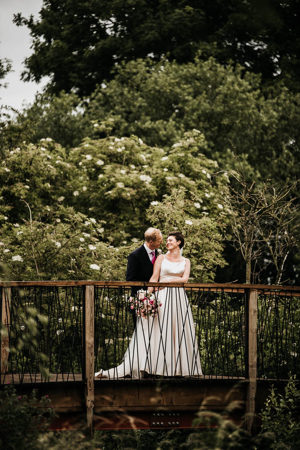Bride and groom on bridge holding each other close for a special moment at Hardwick Moat Weddings
