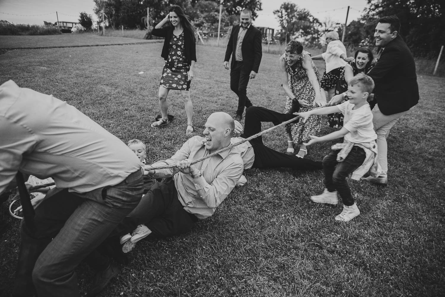 People falling over in a game of tug of war at a wedding.