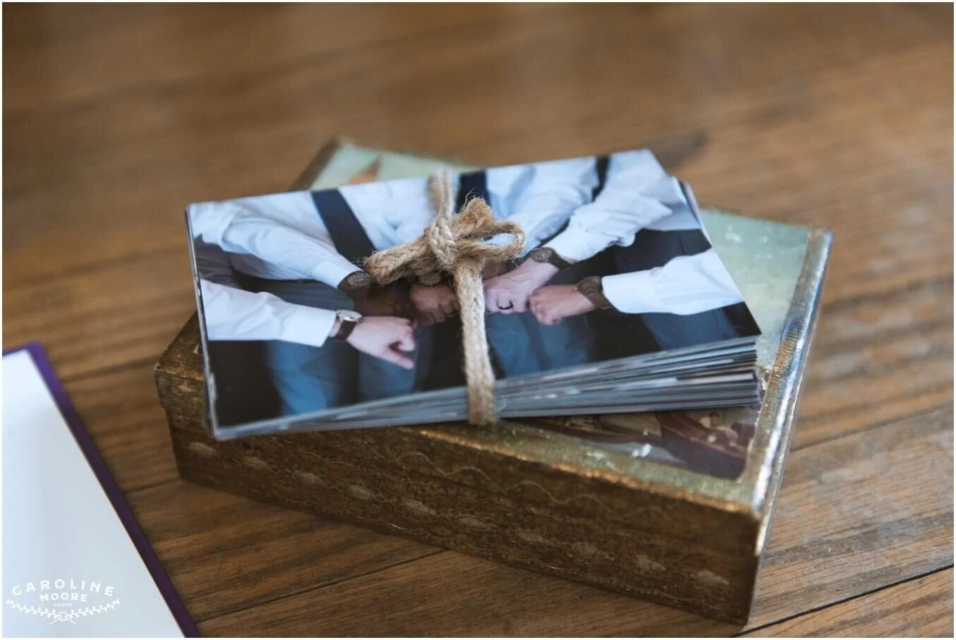 a pile of 5x7 photos held together with rustic looking rope, on top of a decorative box