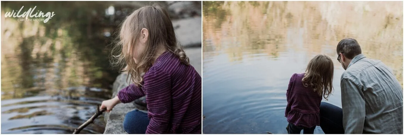 A toddler goes fishing in a lake with her stick, next to her dad