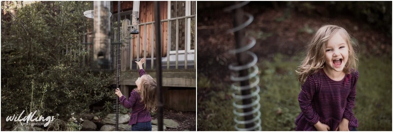 A toddler is laughin, and trying to reach a bird feeder
