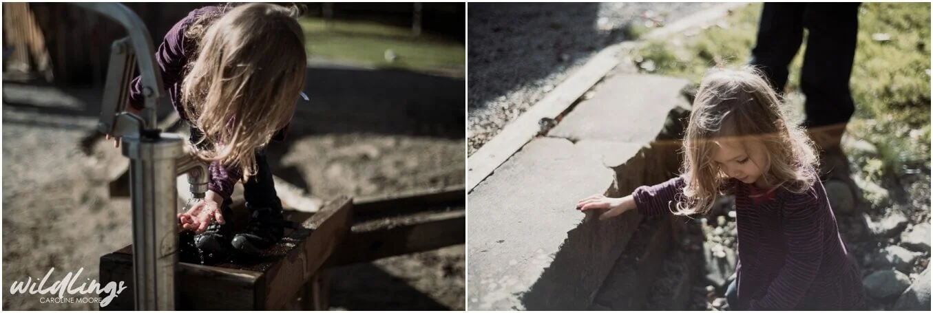 A toddler explores the water pump while her long hair falls in her face