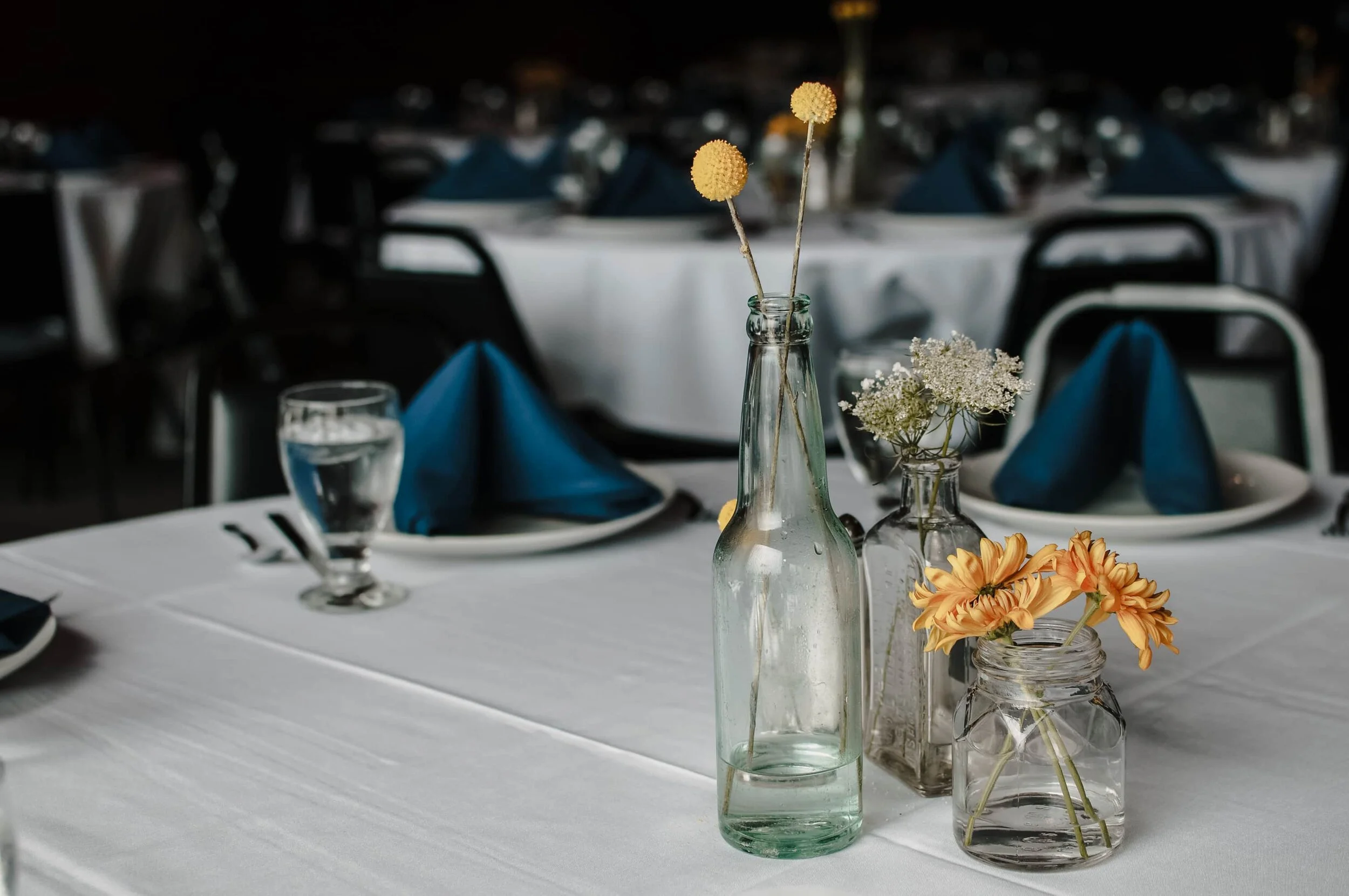 Wildflowers are placed into glass bottles the bride's father found on his hikes in the woods, they are simple and beautiful as a table detail