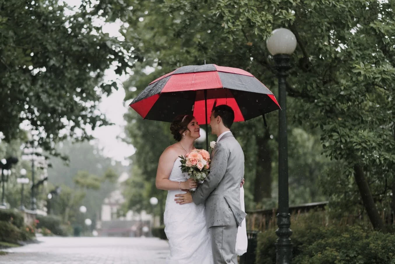 bride and groom smiling at each other beneath a large umbrella