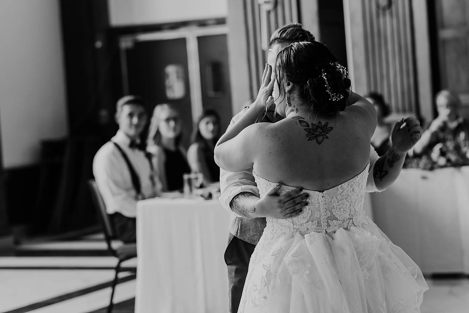 bride wipes away a tear while dancing with her groom